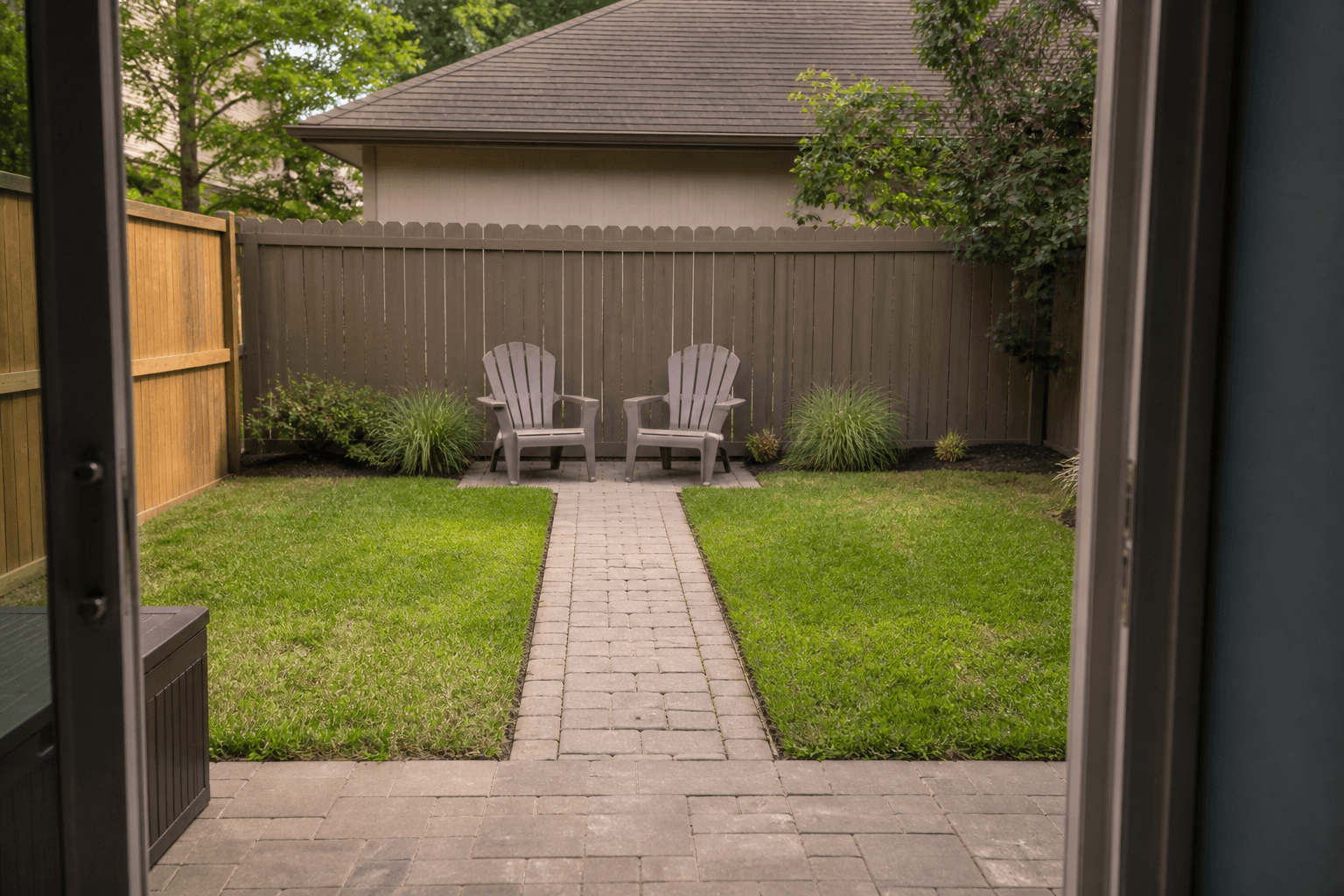 View through a slider to a paver path ending at two chairs against a fence, feng shui backyard layout