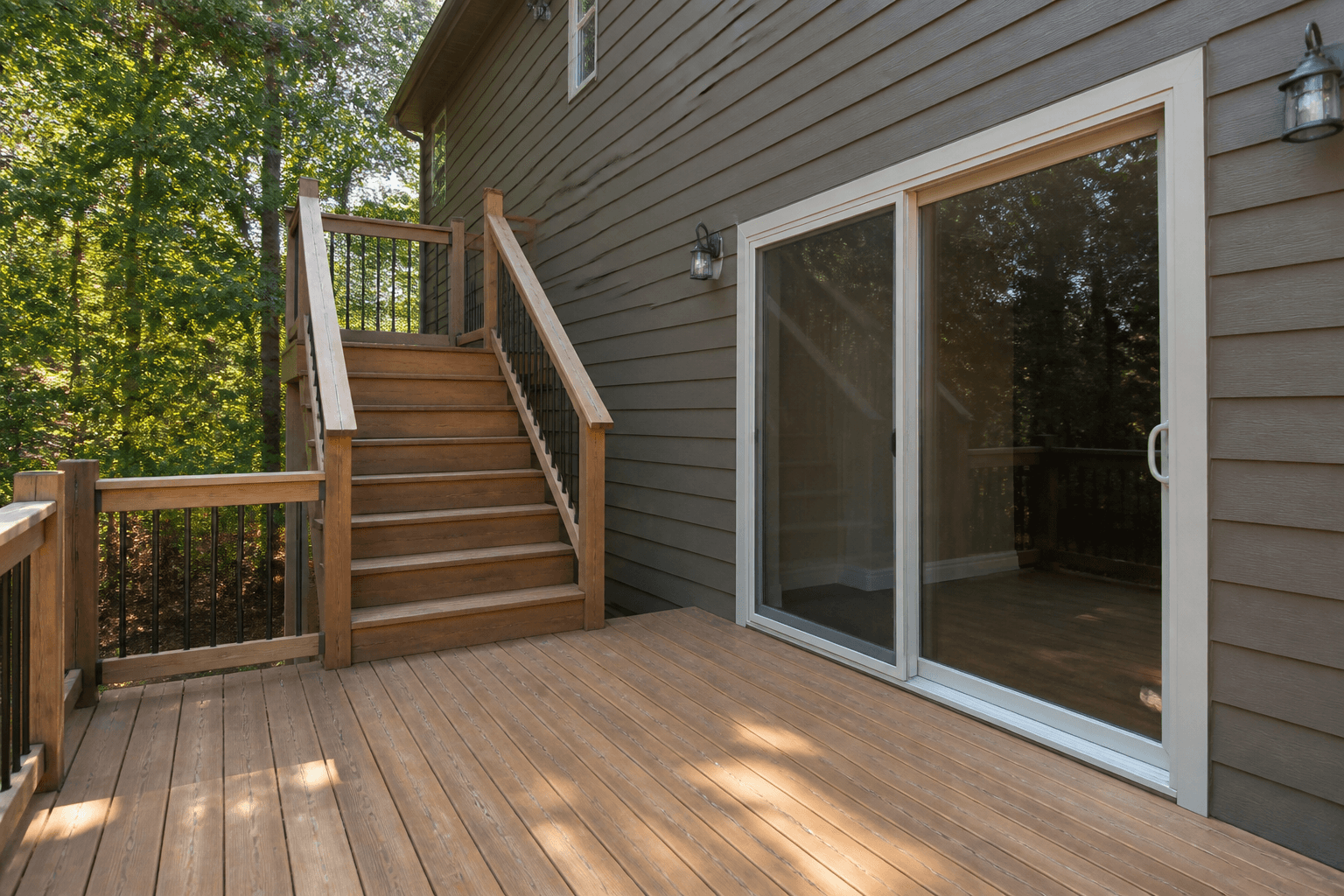 Wood deck stairs landing to the side of a sliding door with a clear handle