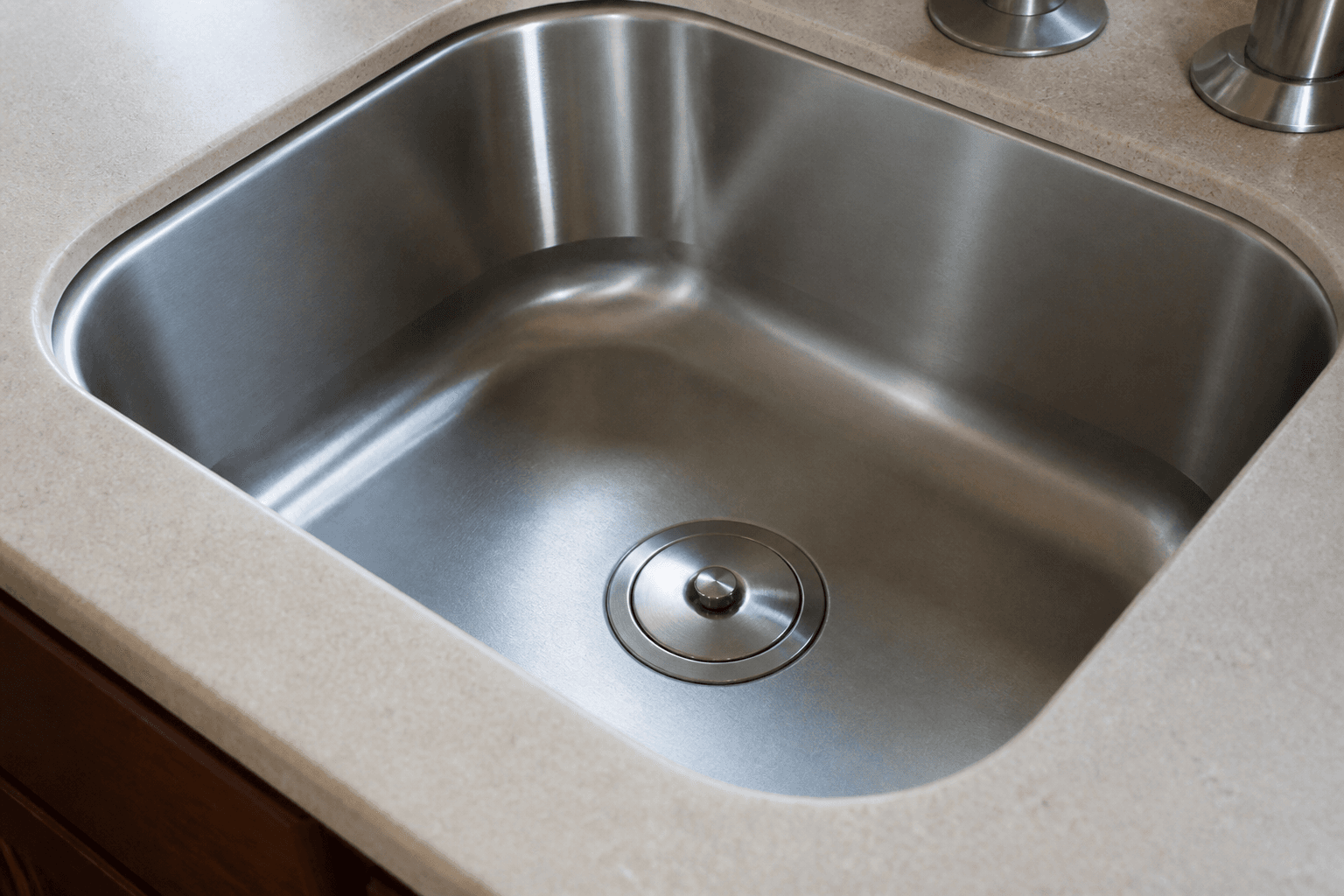 Metal drain stopper seated in a stainless kitchen sink
