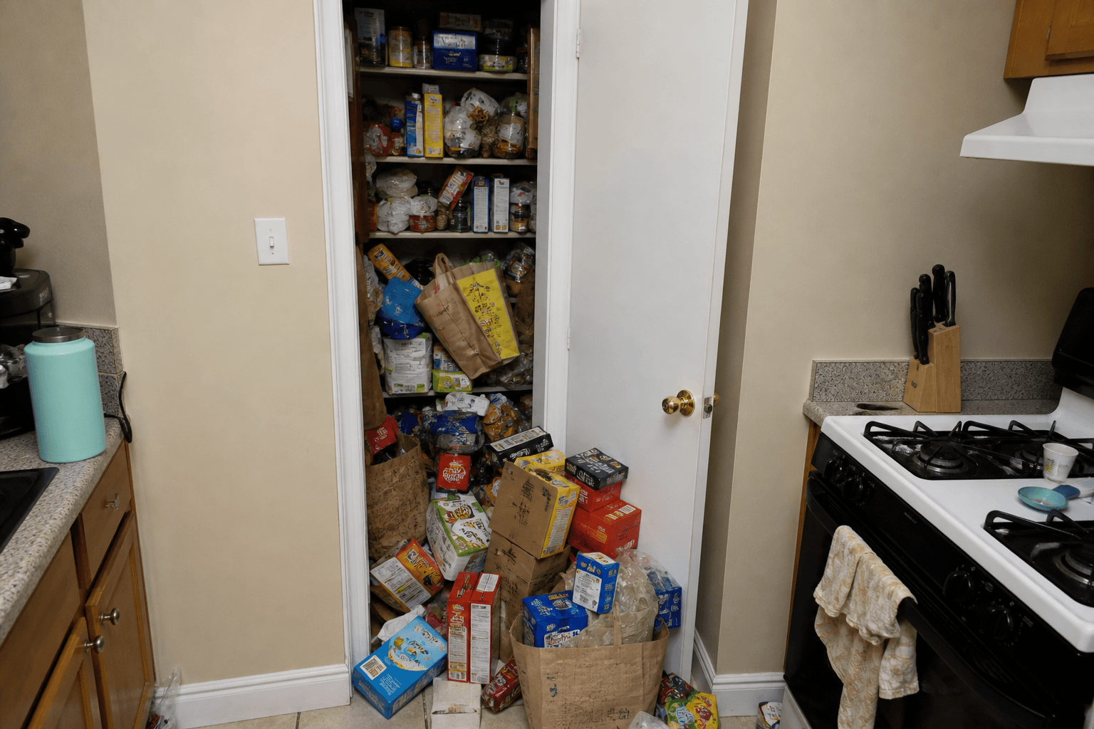Open pantry spilling bags into the cook aisle beside a stove