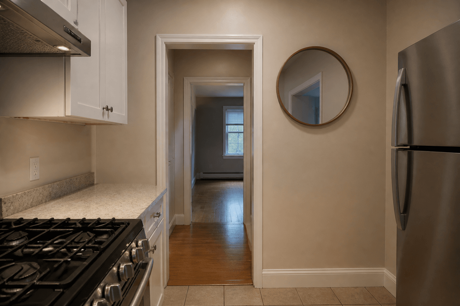 Round gold-framed mirror on a beige kitchen wall showing the doorway, range at the left