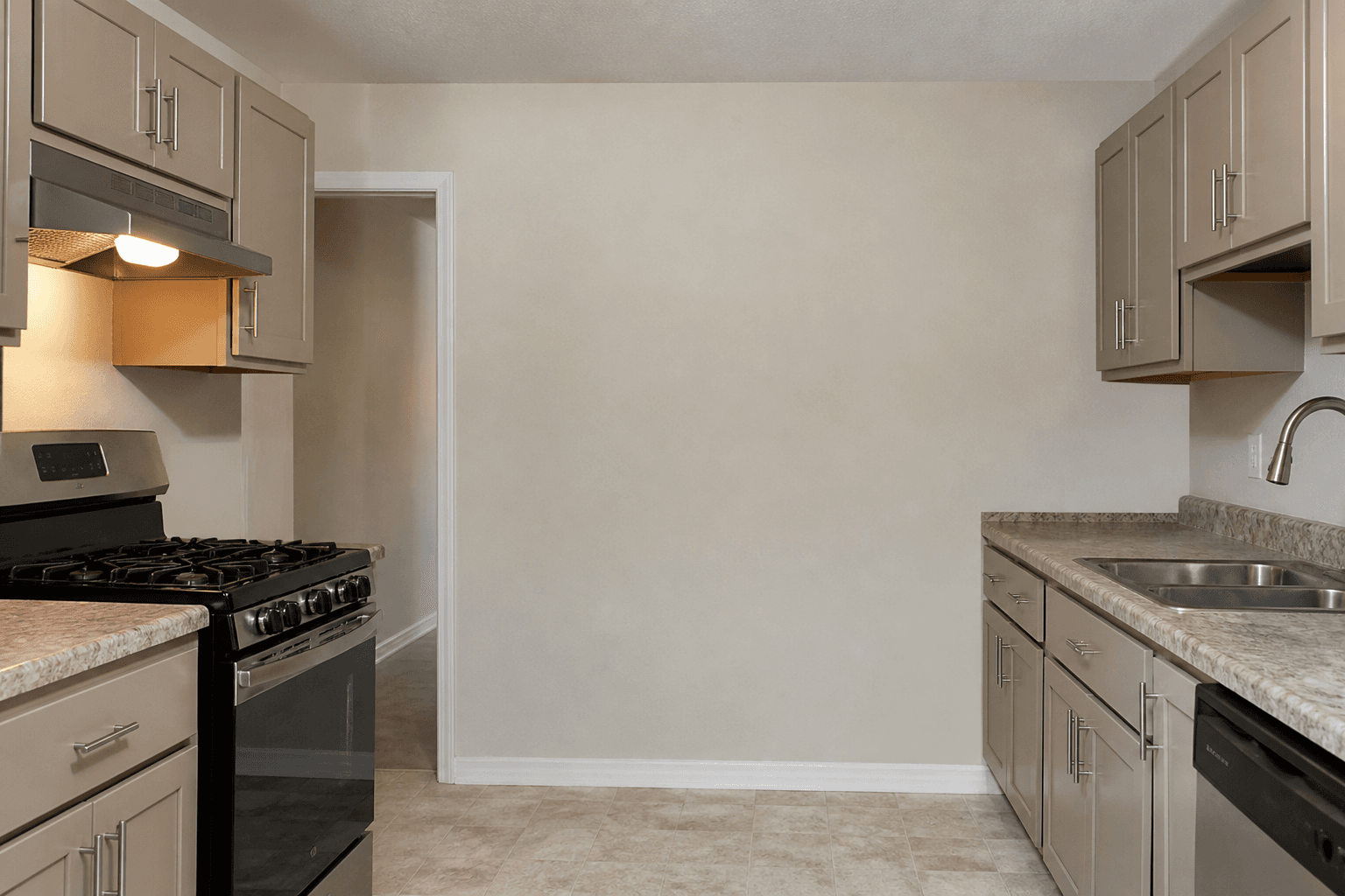 Kitchen range on the left with the cook stance facing a beige wall, doorway behind the shoulder