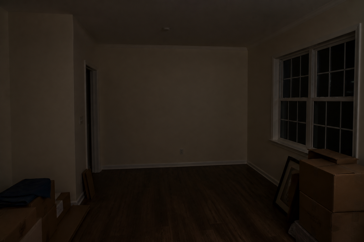 Dark living-room corner at night with boxes and no lamp