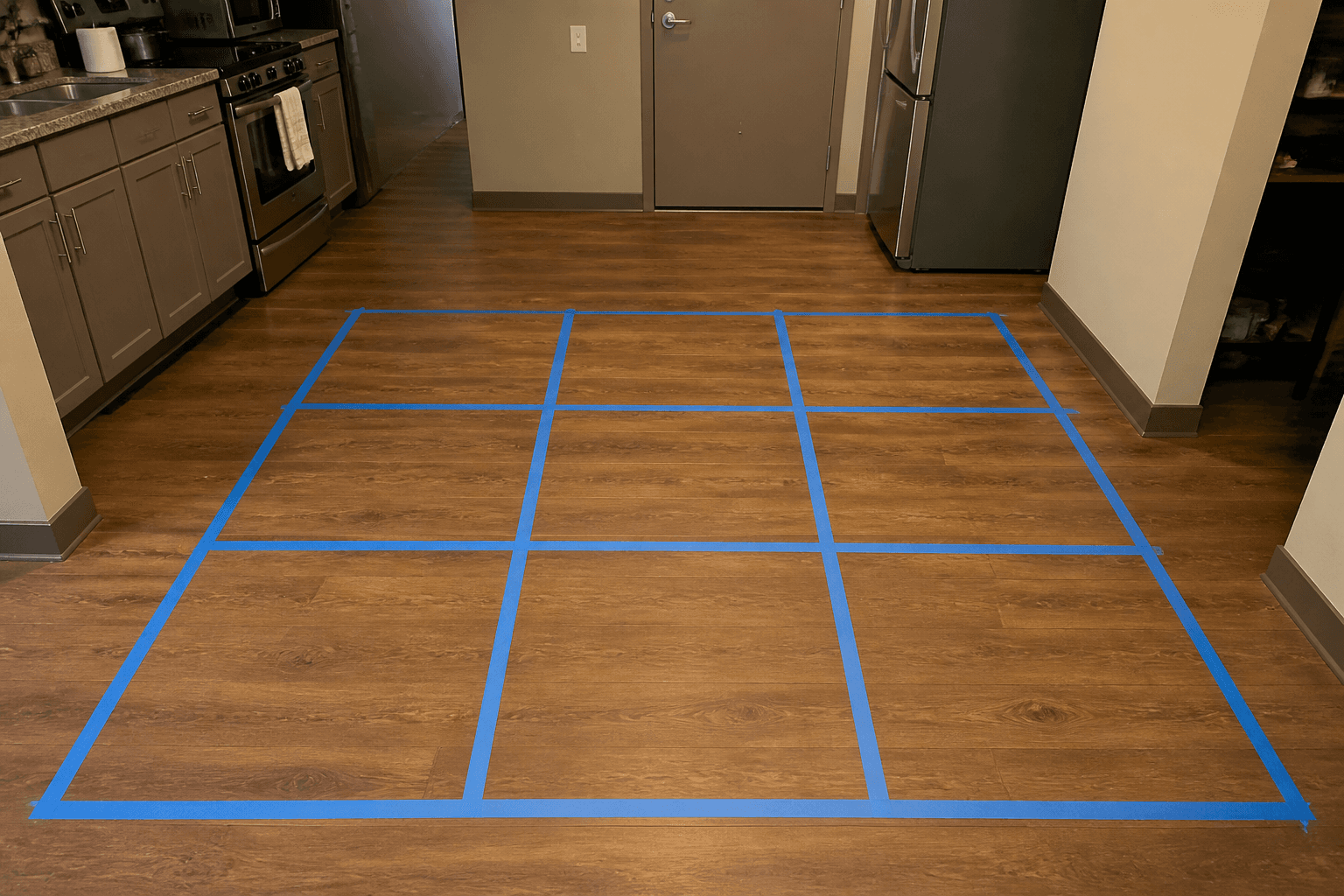 Painter tape making a 3x3 grid on a studio wood floor with the door at the bottom
