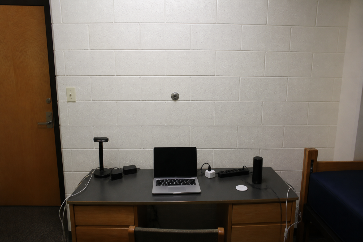 Desk facing a blank wall with the chair back to the dorm door