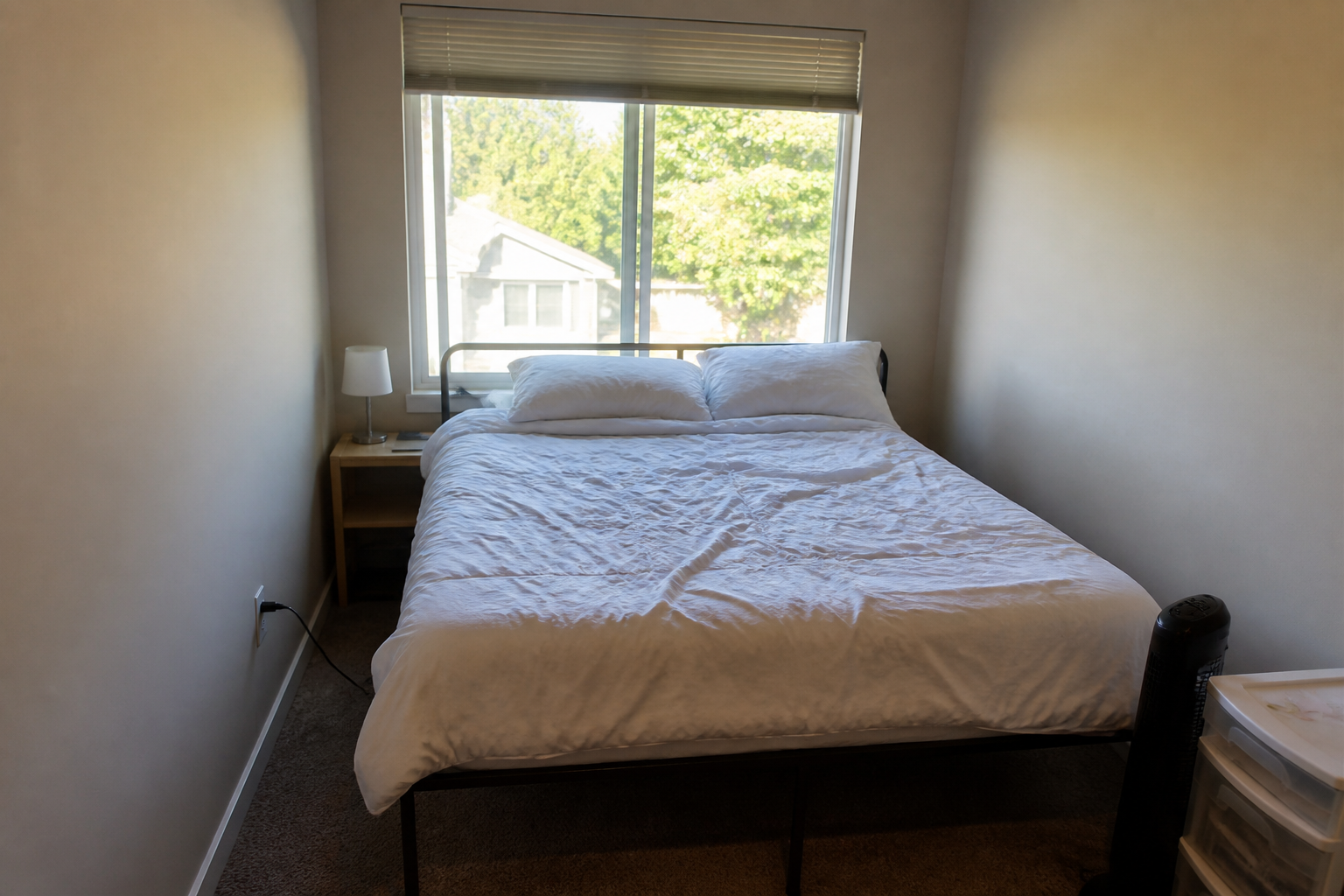 Metal bed frame with no headboard pushed against a bright window as the only backing