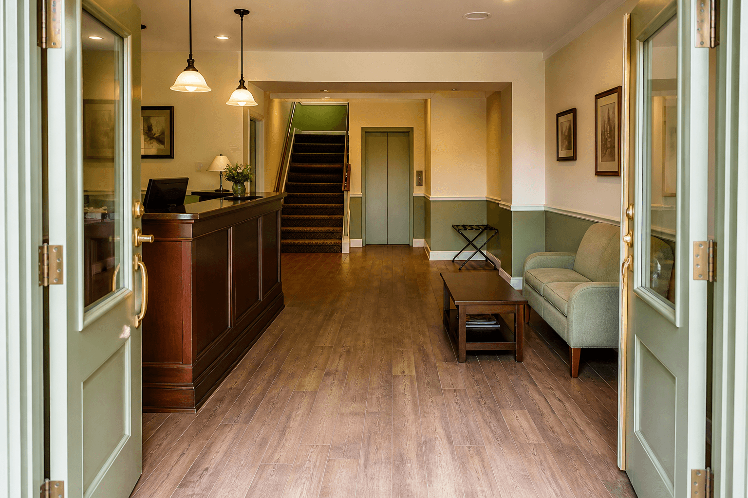 Small inn lobby from open sage doors, wood desk at left, sofa at right, clear walk to stair and lift, Feng Shui hotel lobby