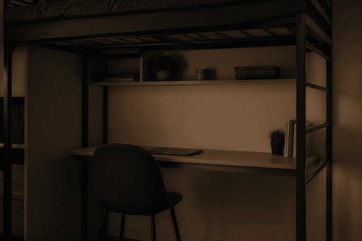 Laptop closed and chair tucked under a loft-bed desk