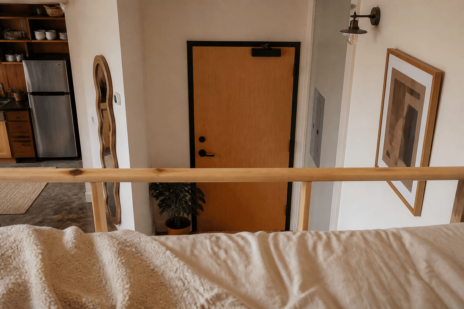 View from a loft mattress toward a wood apartment door over a rail