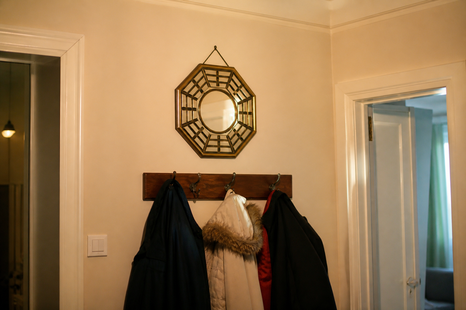 Octagonal bagua mirror with trigrams hanging inside above a coat rack