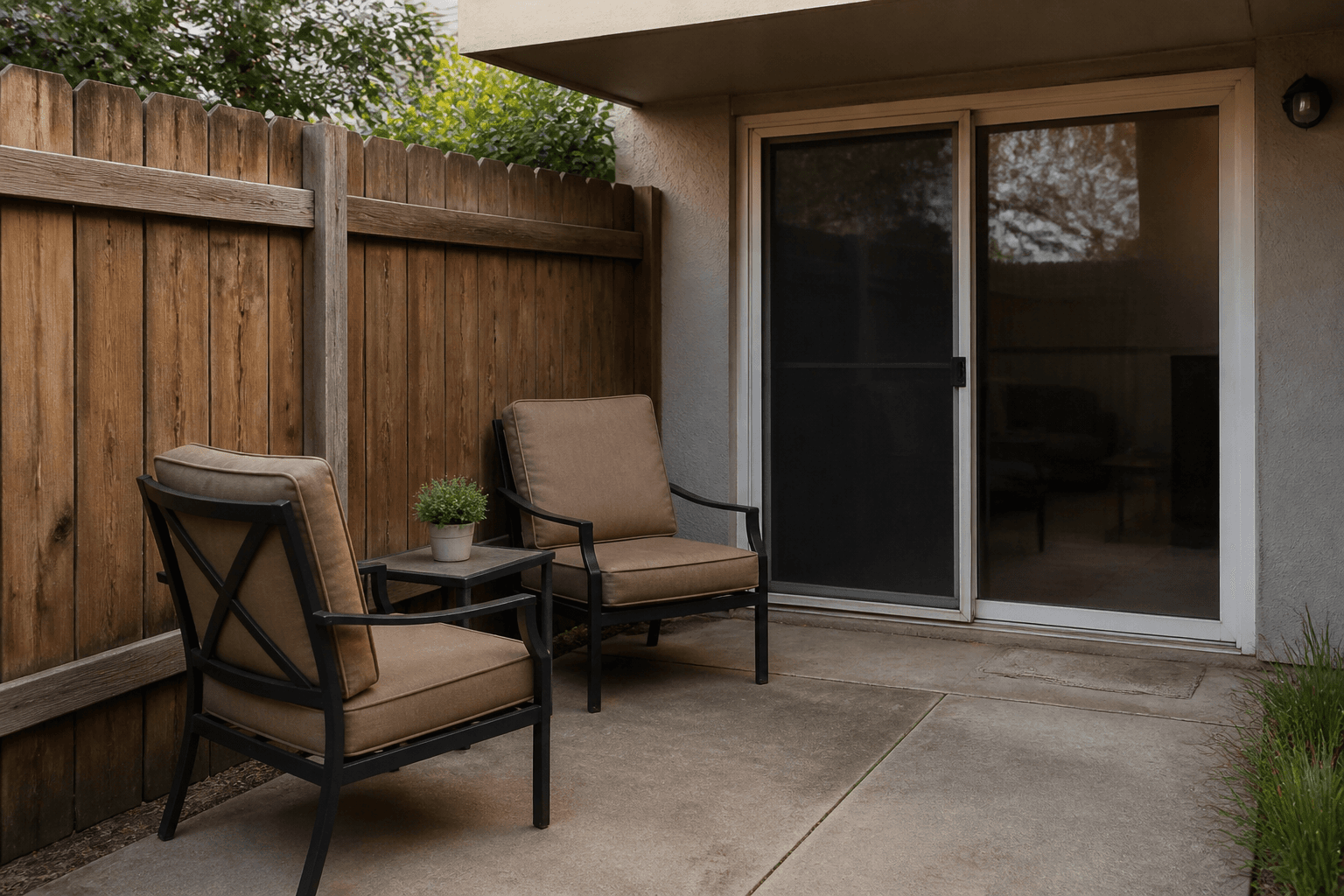 Outdoor chairs with backs to a fence, seats facing the house sliding door
