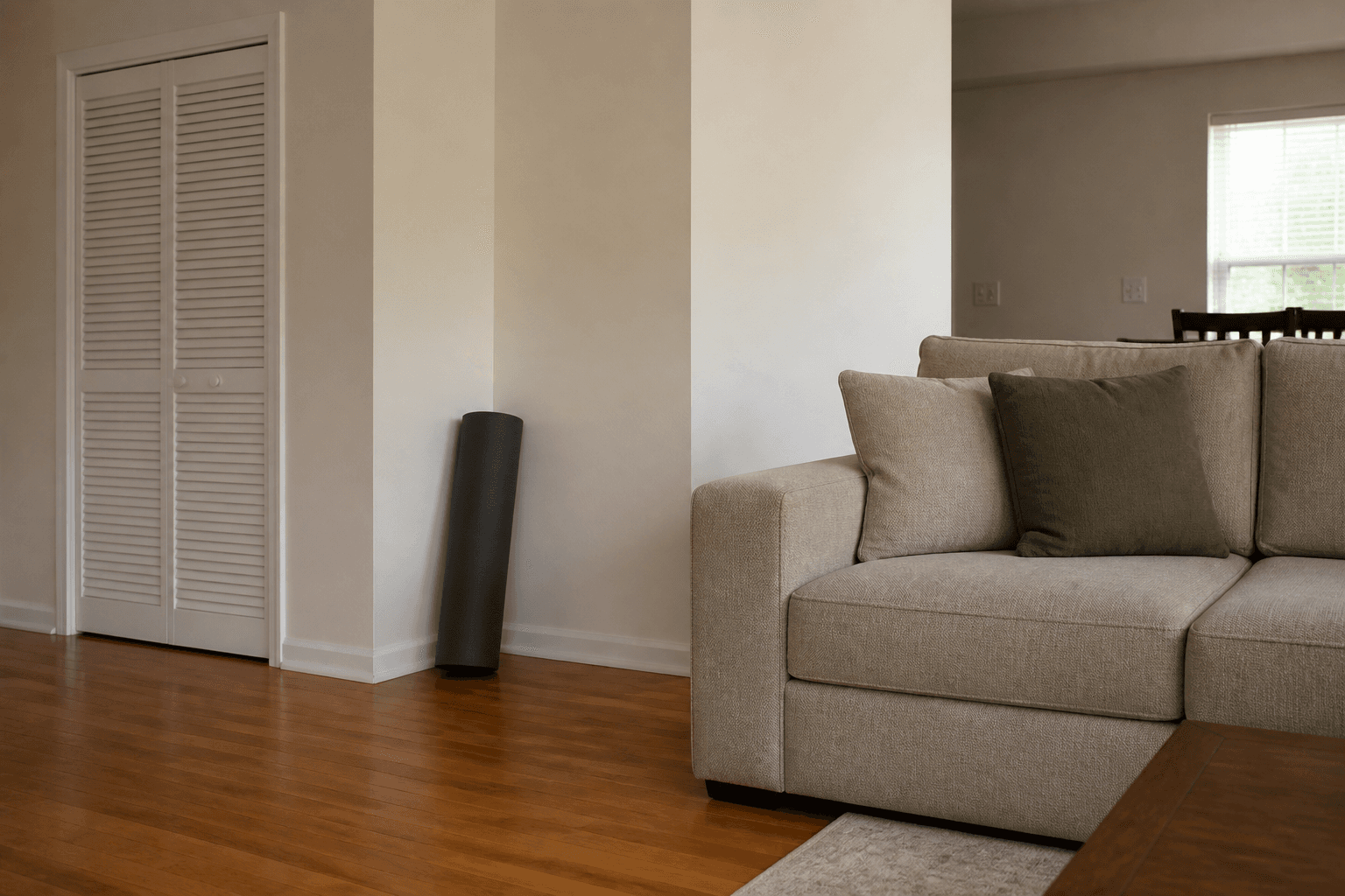 Rolled yoga mat in a living-room corner beside a beige sofa, feng shui yoga space