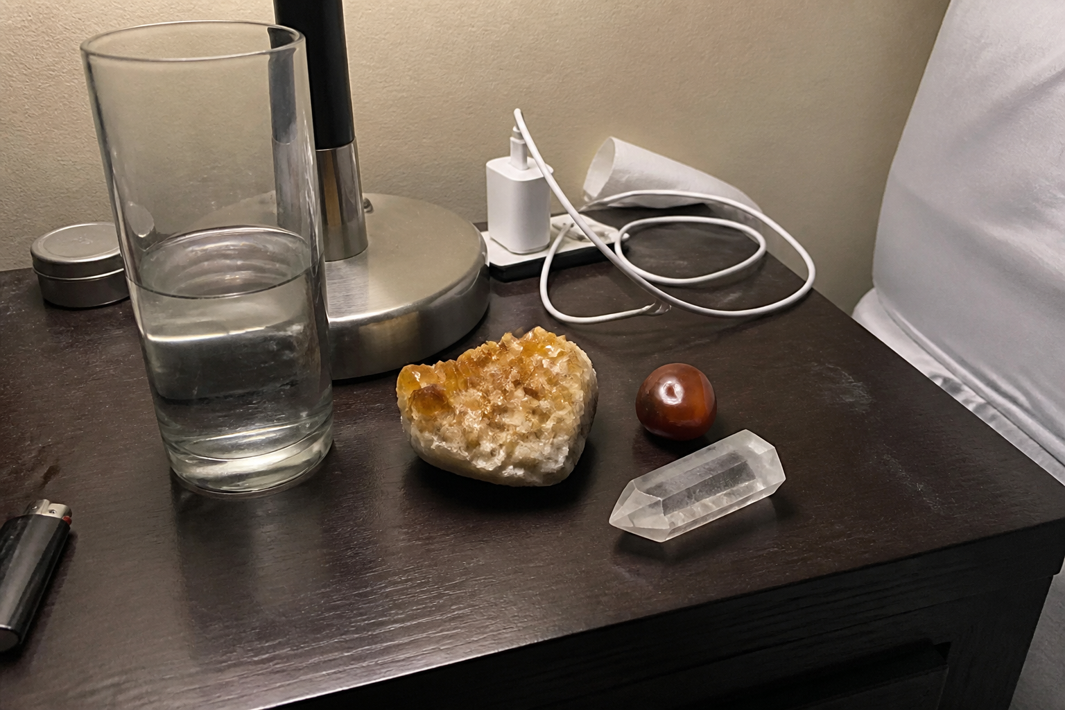 Citrine cluster, carnelian, and a pointed quartz crowded on a nightstand with a phone charger