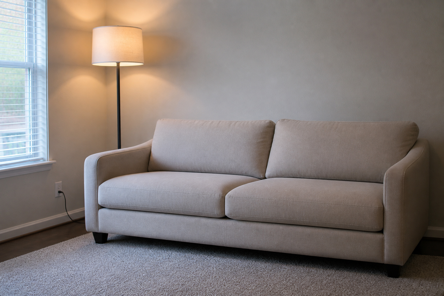 Beige sofa in cool north light with a floor lamp switched on beside it