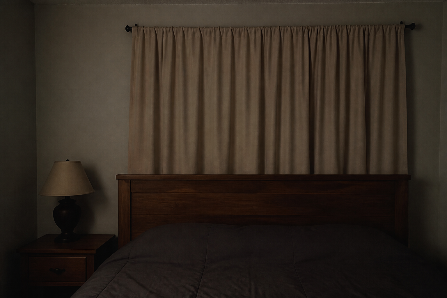 Heavy oatmeal drape closed on a tension rod in front of a wood panel headboard